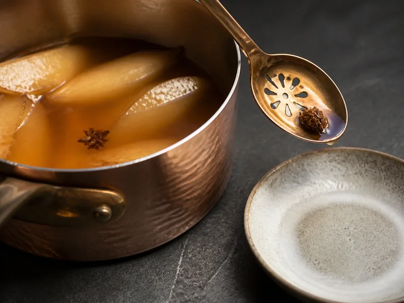 One star-anise point infusing in amber poached-fruit syrup with a removal spoon - star anise for anise seed | KnowTheSpices