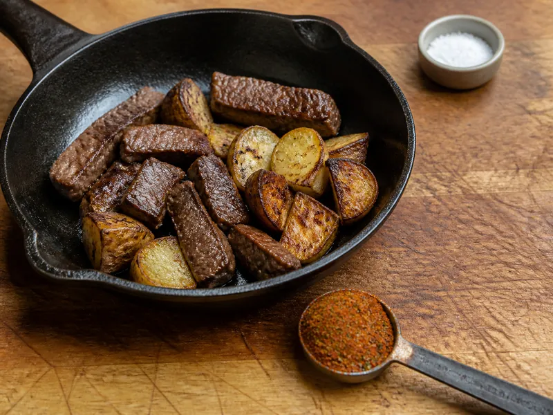 Measured Cajun seasoning beside unsalted seared beef and potatoes - Cajun seasoning as a berbere substitute | KnowTheSpices