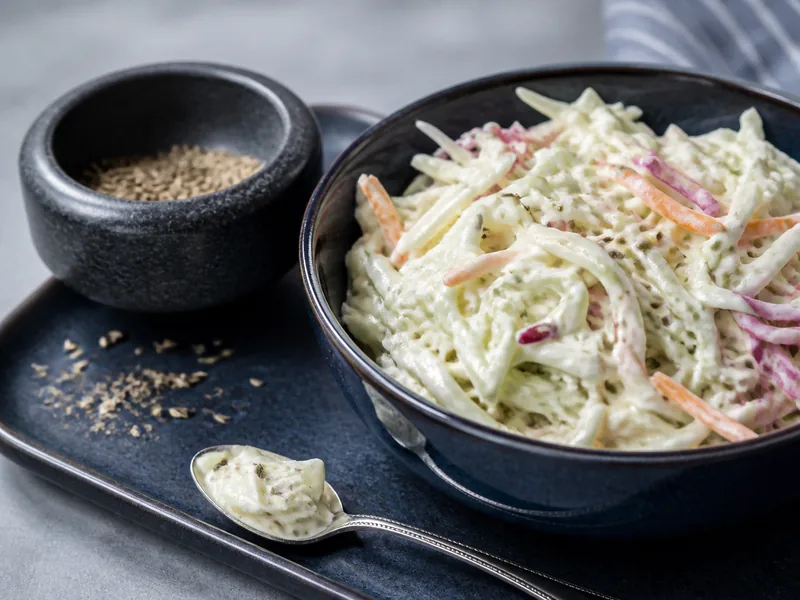 Cracked dill seeds dispersing into creamy coleslaw dressing - celery-seed-substitutes | KnowTheSpices