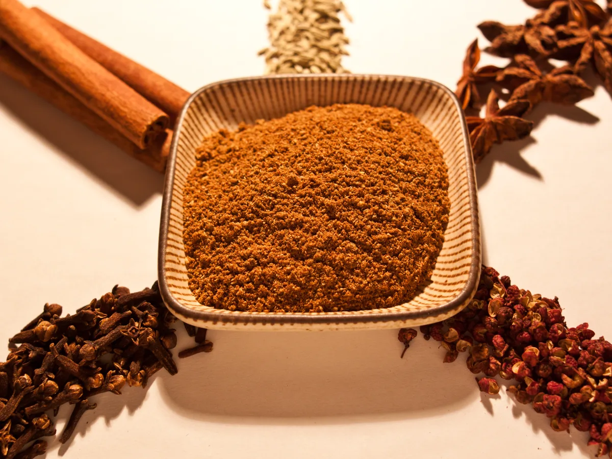Five-spice powder surrounded by star anise, Sichuan peppercorns, cloves, cinnamon, and fennel seed - Chinese five-spice substitutes | KnowTheSpices
