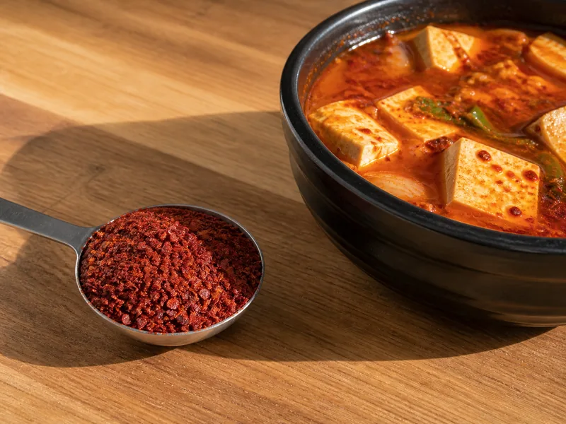 Coarse Aleppo pepper measured beside a Korean tofu stew - gochugaru substitutes | KnowTheSpices