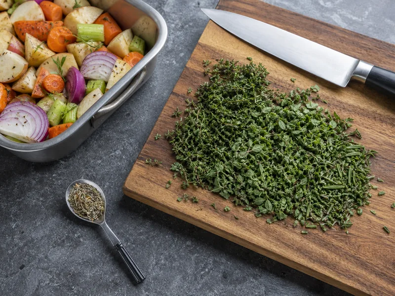 A small dried-herb spoon beside a larger pile of chopped fresh herbs - herbs de Provence substitutes | KnowTheSpices