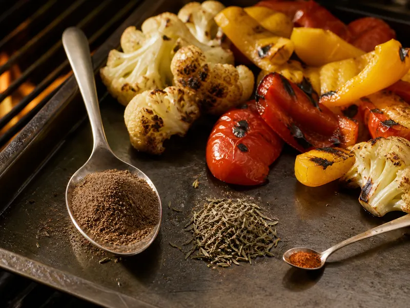 Large allspice and thyme measures with a small cayenne spoon beside grilled vegetables - jerk seasoning substitutes | KnowTheSpices