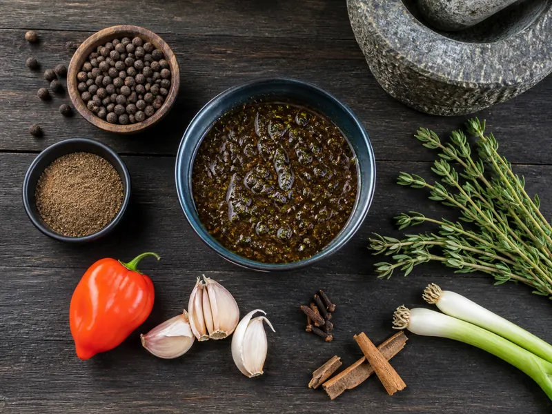 Allspice, thyme, chile, garlic, and warm spices around a dark jerk-style marinade - jerk seasoning substitutes | KnowTheSpices