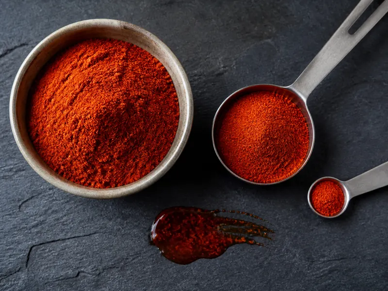Deep red chile powder facing a large paprika measure and a small cayenne measure - Kashmiri chili powder substitutes | KnowTheSpices