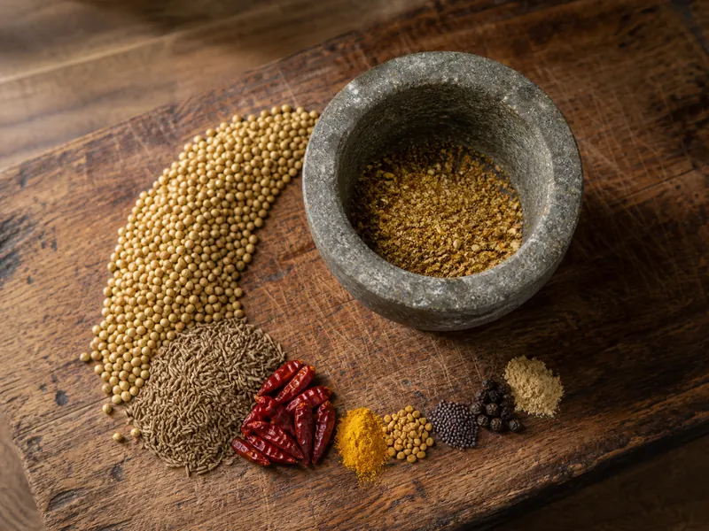 Coriander-led spice measures arranged around a mortar for homemade Madras-style curry powder - Madras curry powder substitutes | KnowTheSpices