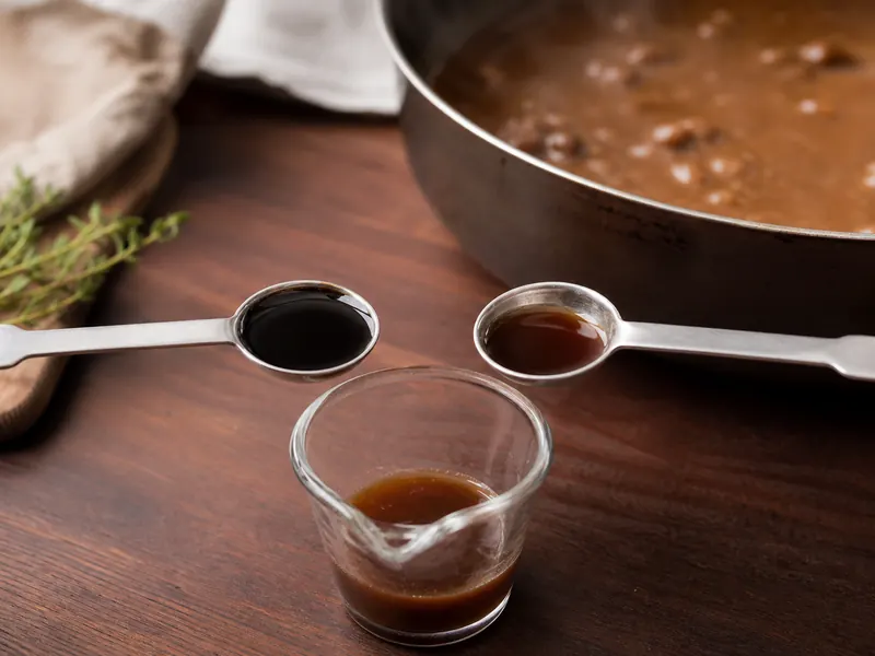 Two half-teaspoon portions of soy and Worcestershire sauce joining in one measuring cup beside beef gravy