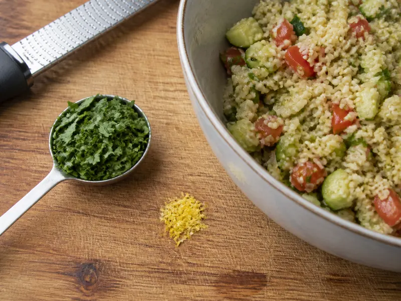 A large chopped parsley measure and small lemon-zest pinch entering bulgur grain salad