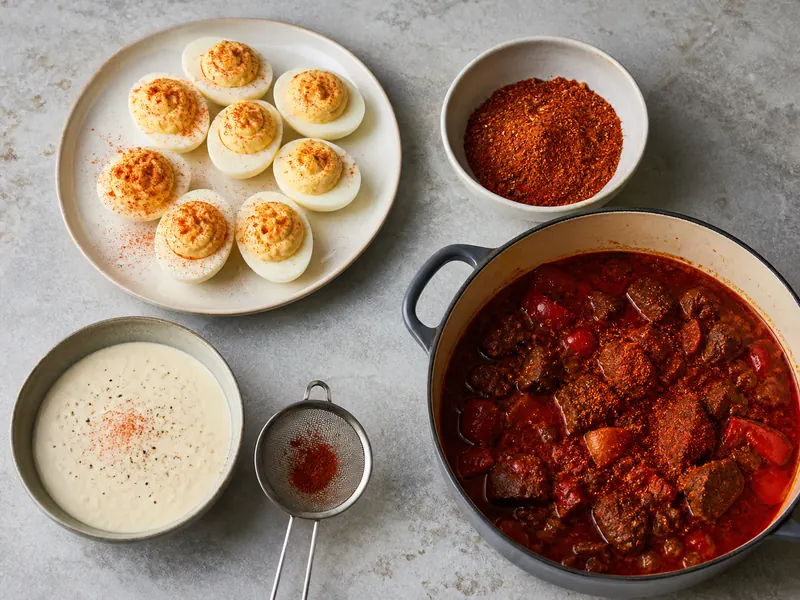 Deviled eggs, a dry meat rub, red stew, and pale cream sauce with separate red powder applications