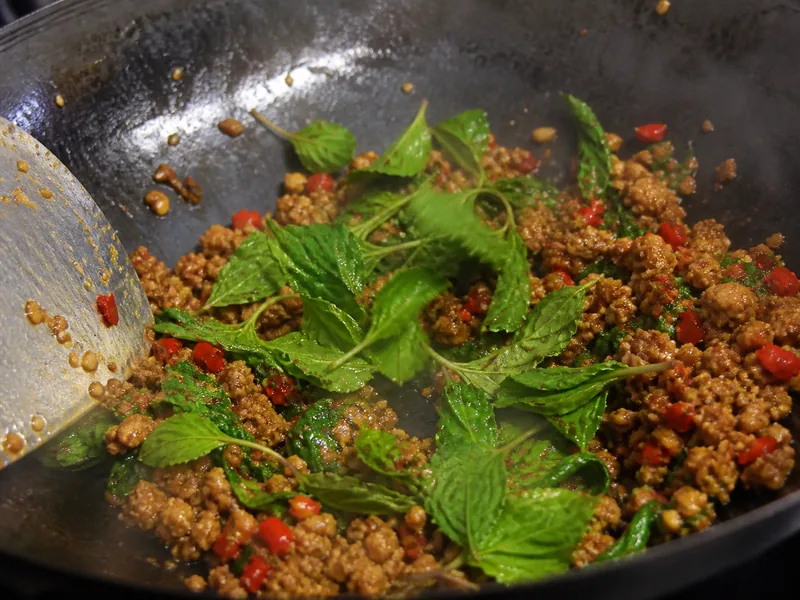 Holy basil leaves wilting into a garlic chile meat stir-fry - thai basil substitutes | KnowTheSpices