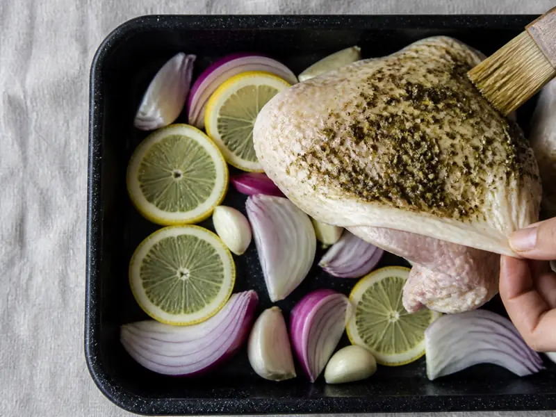 Chicken thigh lifted above lemon and onion with za'atar coating only the upper dry skin - za'atar chicken assembly | KnowTheSpices