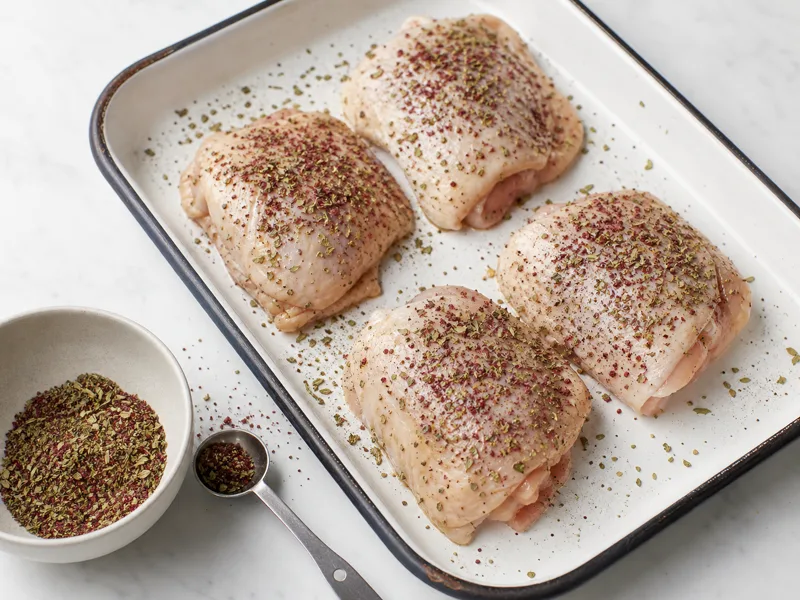Italian seasoning and sumac rubbed into oiled chicken skin on an enamel sheet pan