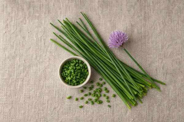 A bunch of fresh chives with purple flowers beside snipped rings - chives | KnowTheSpices