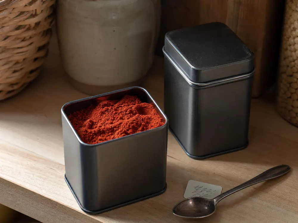 Open dark tin of smoked paprika stored away from light on a pantry shelf