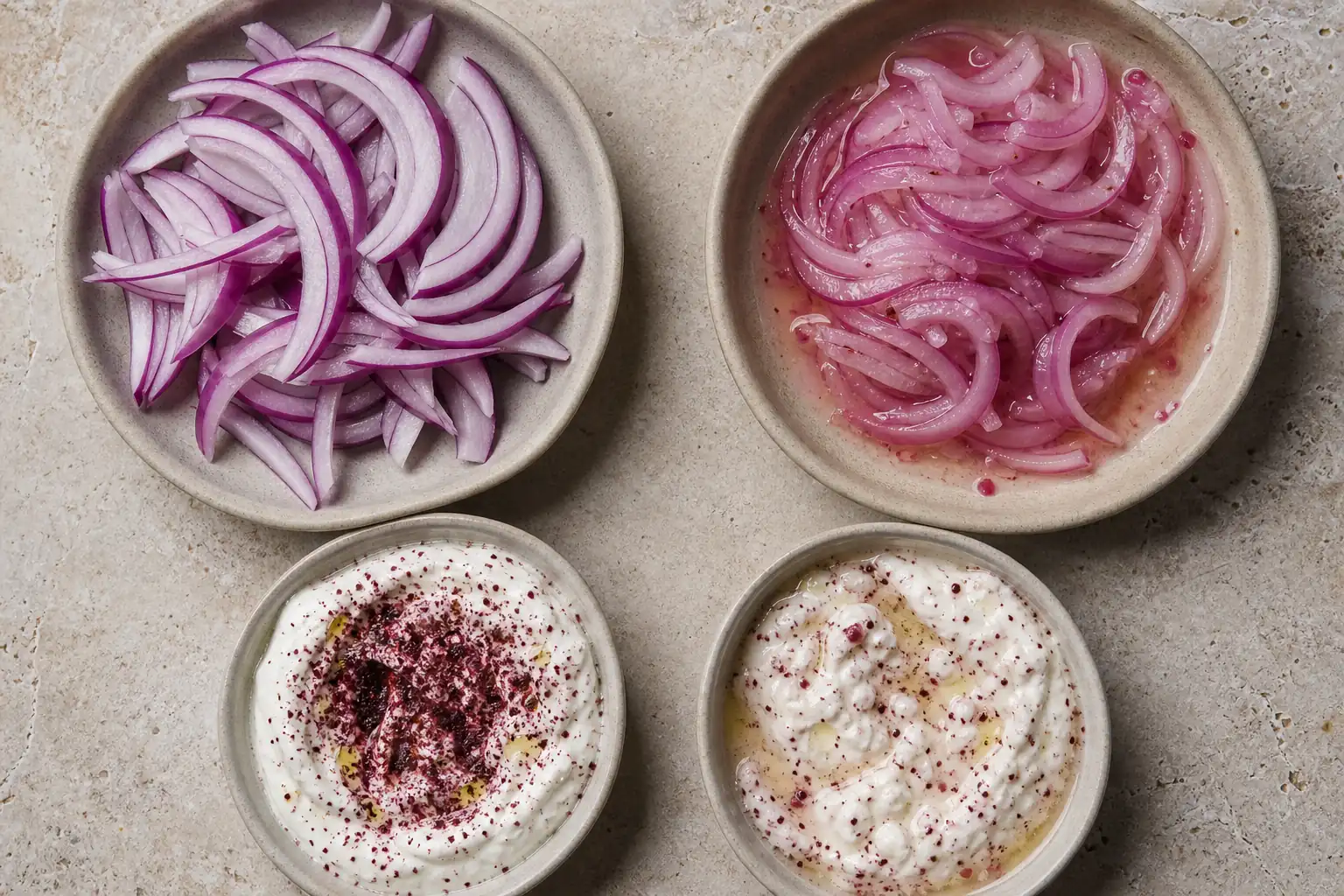 Sumac dusted onions and thick labneh beside wetter lemon dressed samples on a neutral table