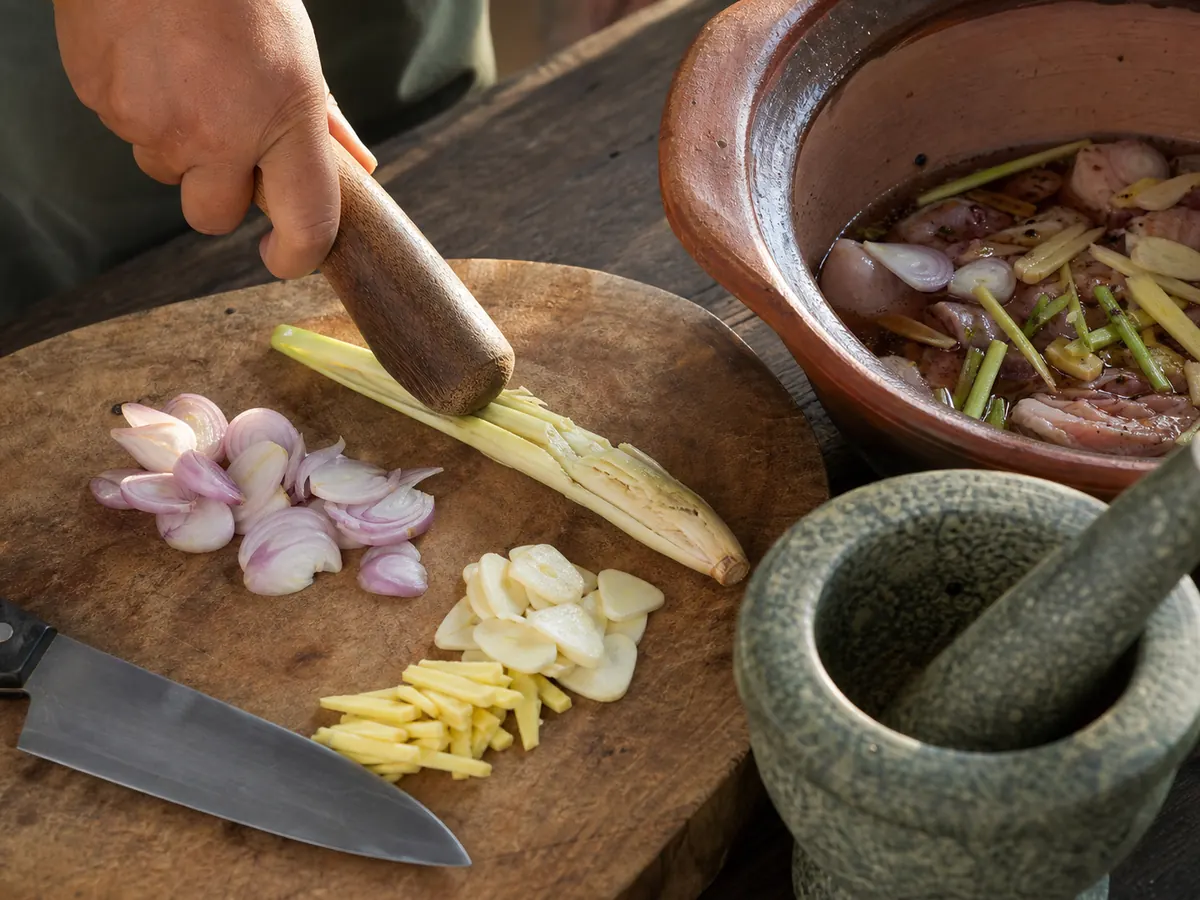 Lemongrass bruised beside shallot, garlic, ginger, and a clay pot marinade - Vietnamese herbs and spices | KnowTheSpices